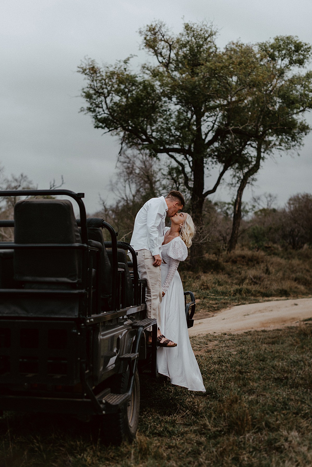 bride and groom kissing on safari vehicle