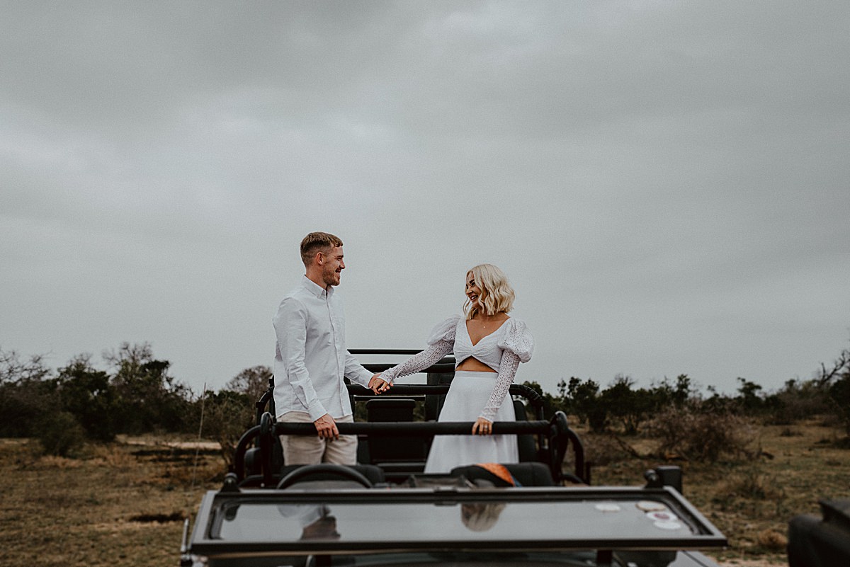 bride and groom holding hands on safari vehicle